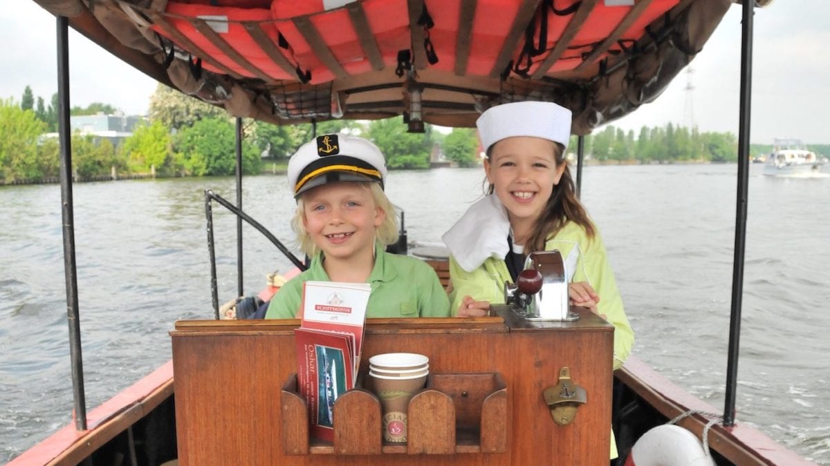 Zwei Kinder hinterm Steuerrad auf dem Boot auf der Spree // HIMBEER